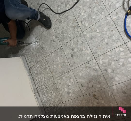 אדם קודח ברצפה עם מקדחה חשמלית